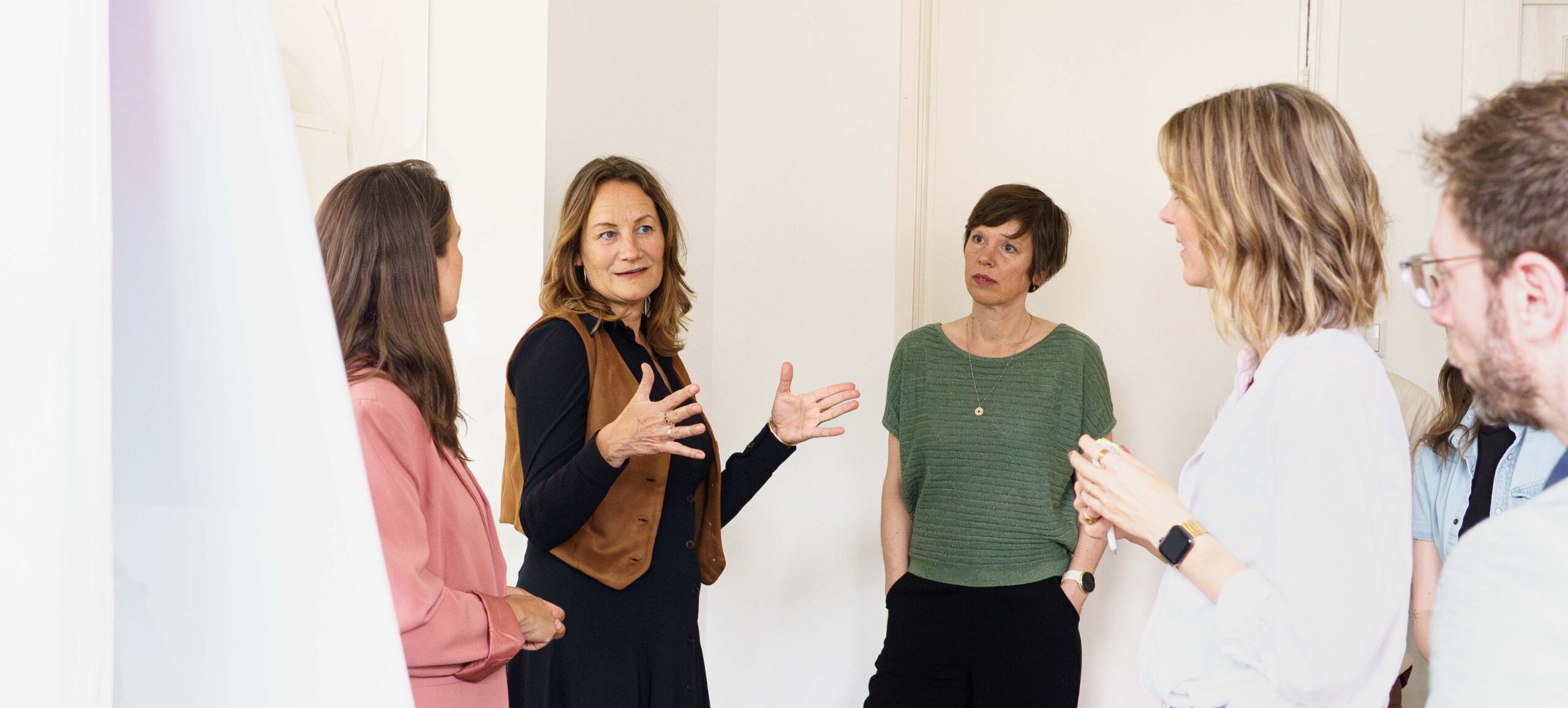Groep mensen praten met elkaar. Iedereen kijkt en luistert naar één persoon.
