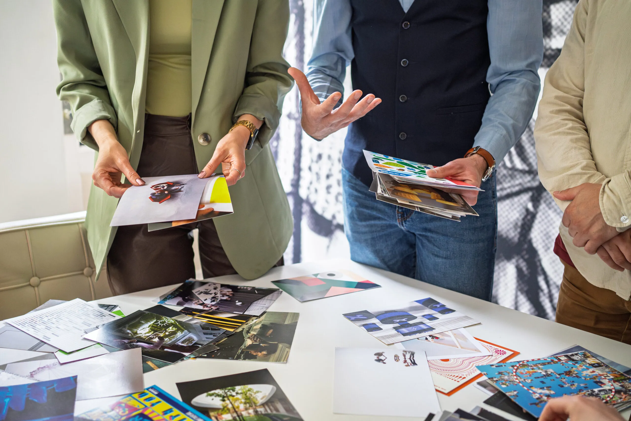 Mensen selecteren en bespreken foto’s op tafel tijdens een creatieve sessie.