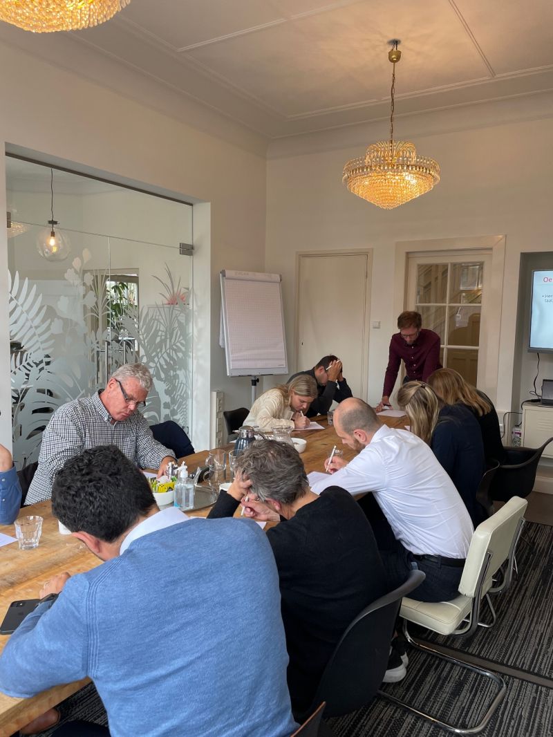Groep mensen gebogen over vellen papier tijdens een schrijftraining bij Einder.