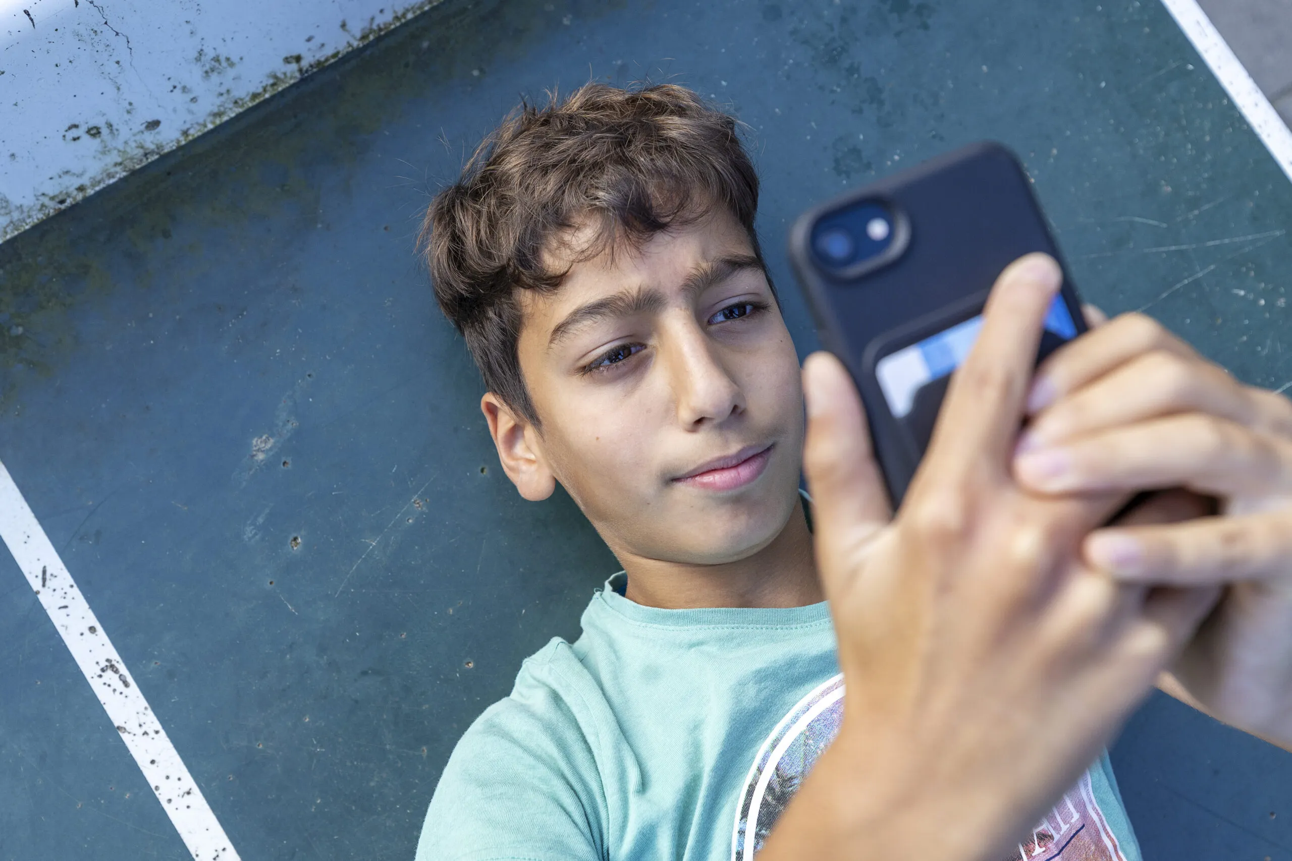 Jonge scholier checkt zijn mobiele telefoon.
