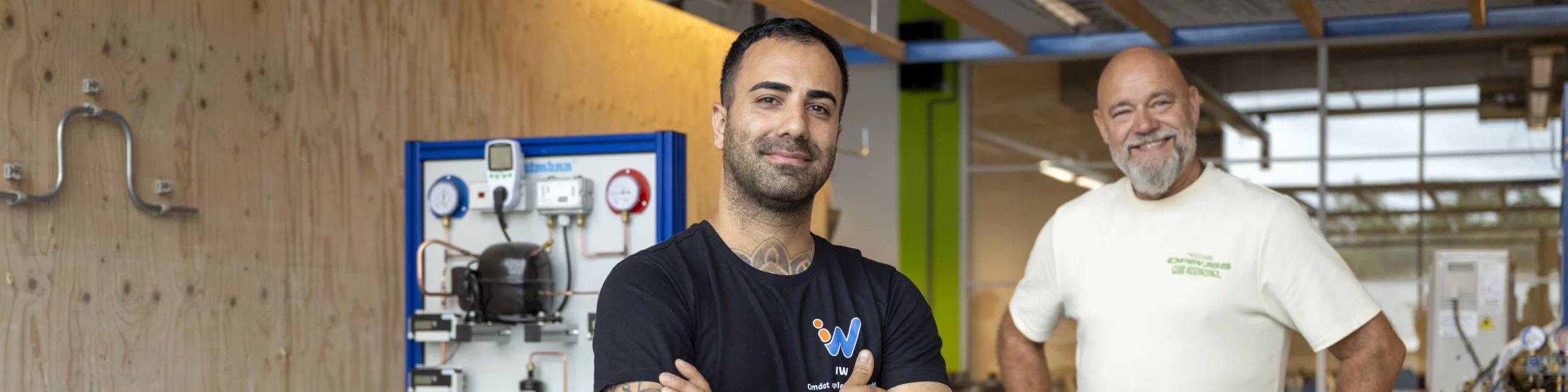 Twee lachende mannen staan in de techniekruimte van het ROC Nijmegen.