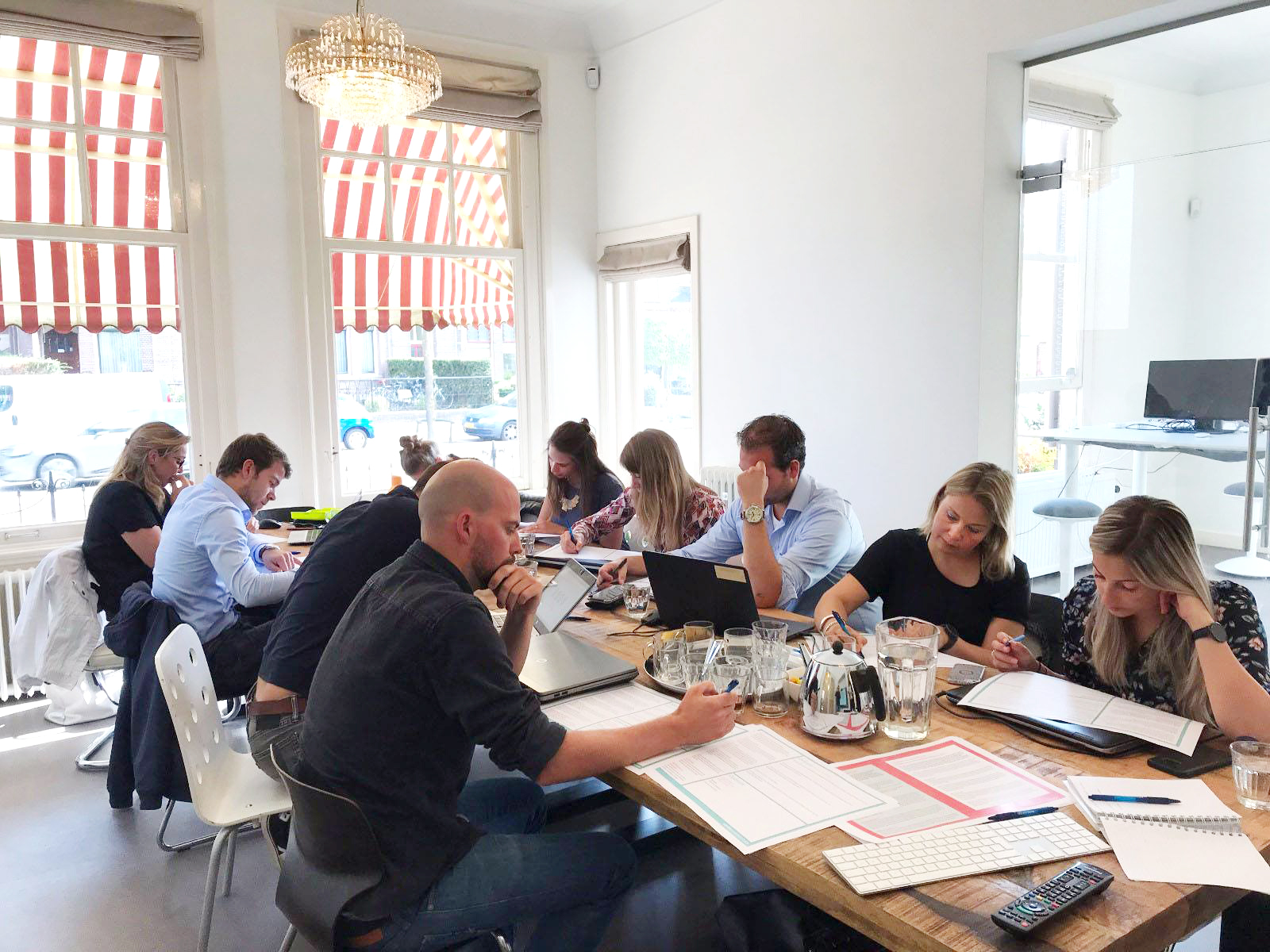 Groep mensen rond een volle tafel met papieren tijdens een schrijftraining bij Einder.