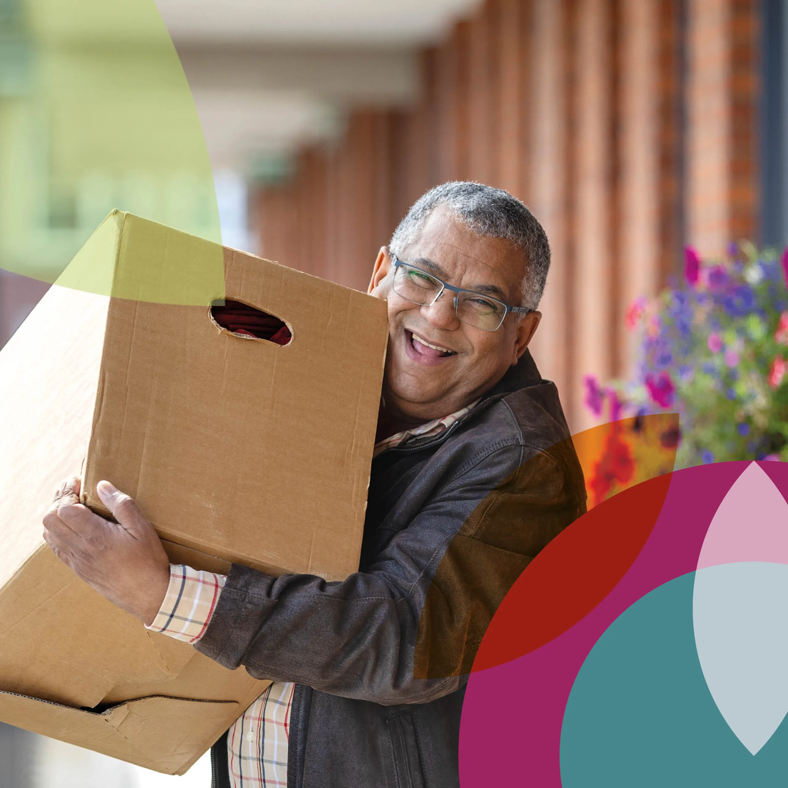 Lachende man kijkt in de camera met een verhuisdoos in zijn handen