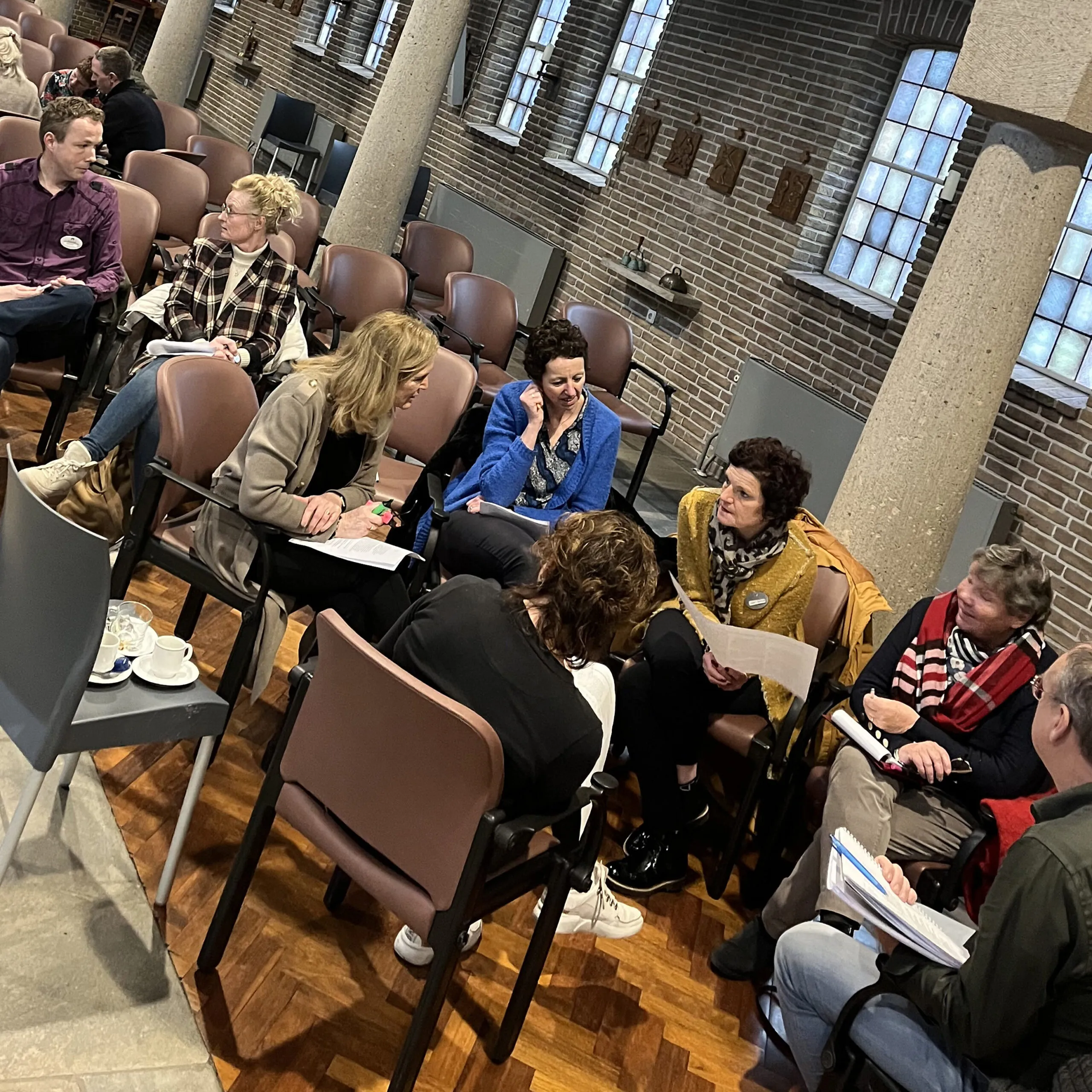 Groep mensen met elkaar in gesprek aan de hand van werkvormen in een mooie kapel